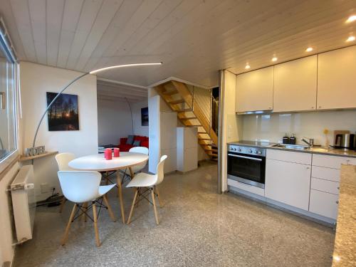 a kitchen with a table and chairs and a staircase at Crans-Montana Stunning Southview Flat in Crans-Montana