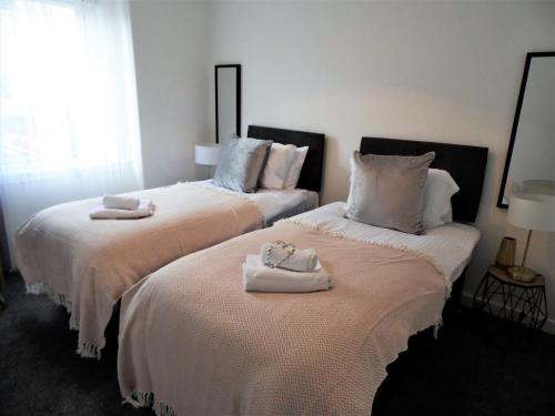 two beds with towels on them in a bedroom at Trident Apartment in Paisley