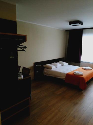 a bedroom with a bed with white sheets and a window at Hotel Dobele in Dobele