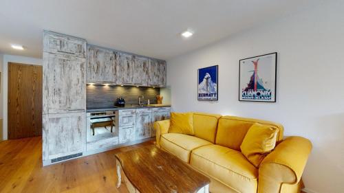 un soggiorno con divano giallo e una cucina di Bright studio with balcony & view to the Matterhorn a Zermatt