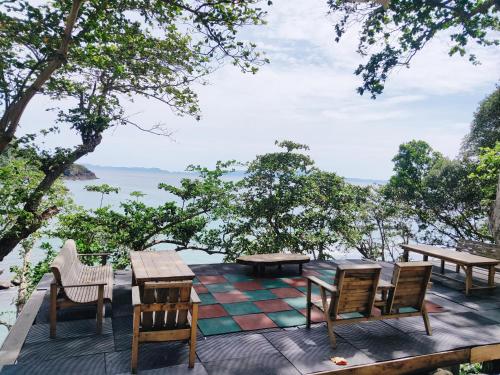 a patio with tables and chairs and a view of the water at Beu Ceubeh Cottage Sabang in Sabong