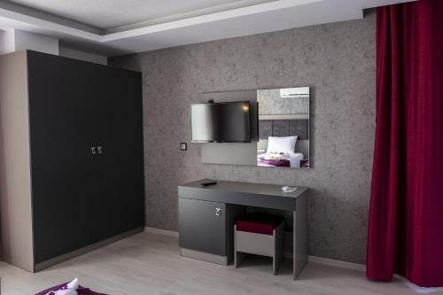 a bedroom with a desk and a mirror and red curtains at TAMARA Business Otel in Antalya