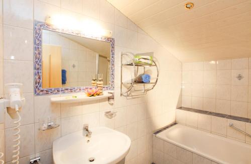 a bathroom with a sink and a mirror and a tub at Sportpension Rubin in Sölden