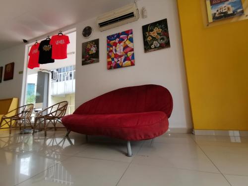 a red couch sitting in a room with chairs at Hotel Abby IGB Tasek in Ipoh