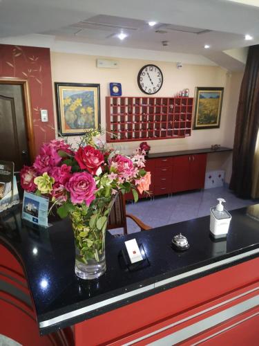 a vase of flowers on a counter with a clock at Hotel Elegance in Belgrade