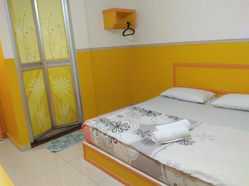 a bed in a room with yellow and yellow walls at Hotel Abby IGB Tasek in Ipoh