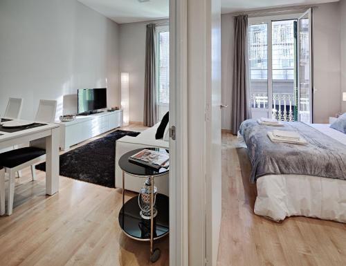 a white bedroom with a bed and a desk and a table at Habitat Apartments Batlló in Barcelona