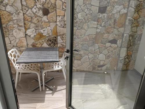 a table and a chair in front of a stone wall at Cavour 19 - Dependance in Torre dell'Orso