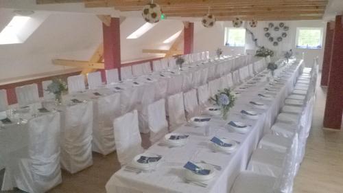 a row of white tables and chairs in a room at Dom Gościnny Bogdany in Barczewo