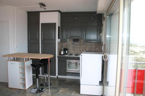 uma cozinha com armários pretos, uma mesa e um frigorífico em LES HORIZONS em Camiers
