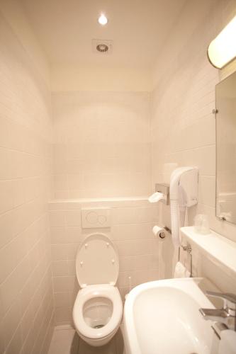 a white bathroom with a toilet and a sink at Nadaud Hotel in Paris