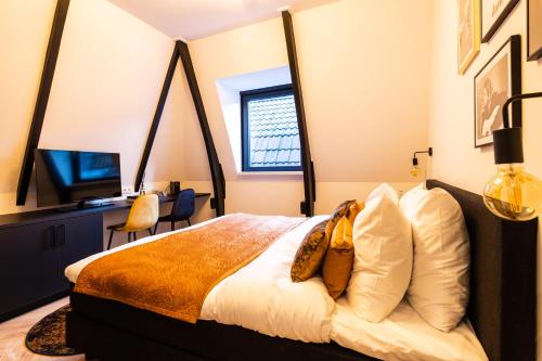 a bedroom with a bed and a desk and a television at Boutique Hotel 43 in Koog aan de Zaan