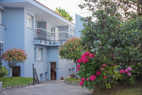 a blue building with pink flowers in front of it at Hotel Sablón in Llanes