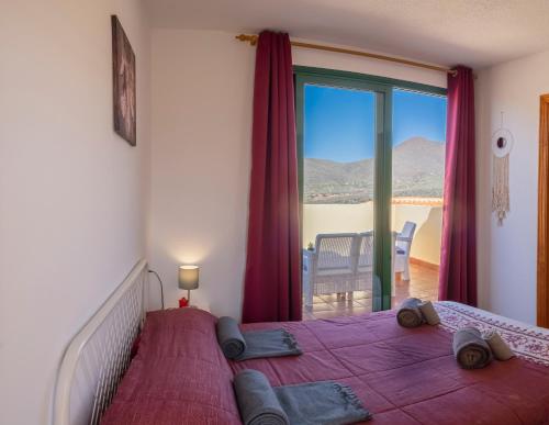 sypialnia z dużym łóżkiem z fioletową pościelą i oknem w obiekcie VistalRoque w Aronie