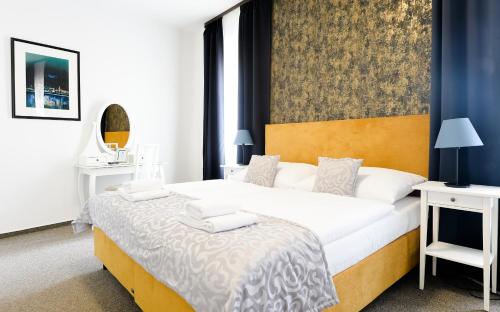 BlueBell Hotel في براتيسلافا: غرفة نوم بسرير كبير وطاولتين بيض