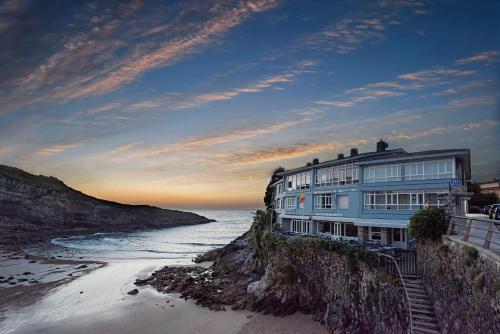 a building on a cliff next to the ocean at Hotel Sablón in Llanes