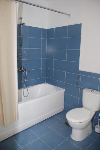 a blue tiled bathroom with a tub and a toilet at Apartments Ismy in Ulcinj