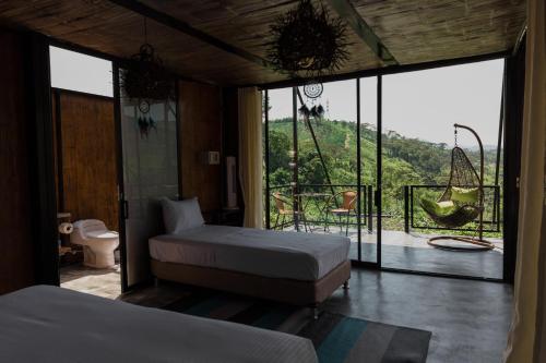 a bedroom with two beds and a balcony with a view at Hotel Resort Del Cafe in Manizales