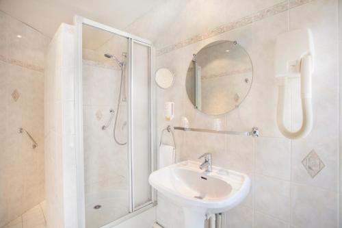 ein weißes Bad mit einem Waschbecken und einer Dusche in der Unterkunft Nadaud Hotel in Paris
