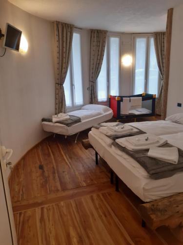 two beds in a room with wooden floors and windows at Locanda Rondolost in Cencenighe