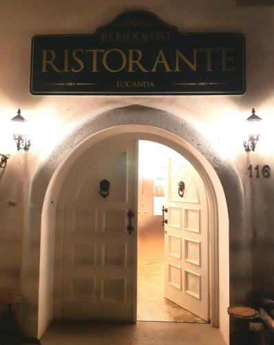 an archway with a sign above a white door at Locanda Rondolost in Cencenighe