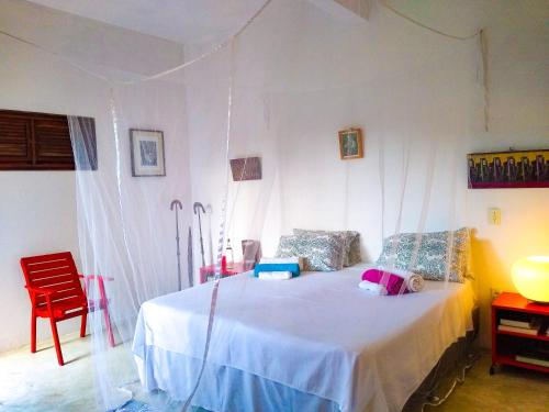 - une chambre avec un lit et une chaise rouge dans l'établissement Castelo Vendôm Ecolodge Parajuru, à Parajuru
