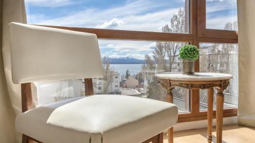 a white chair sitting in front of a large window at Tu Apart en Bariloche 4 in San Carlos de Bariloche