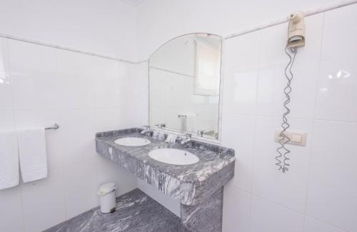 a white bathroom with two sinks and a mirror at Hotel Sablón in Llanes