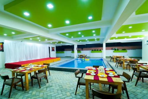 a pool room with tables and a swimming pool at Grand Padappai Residency in Chennai