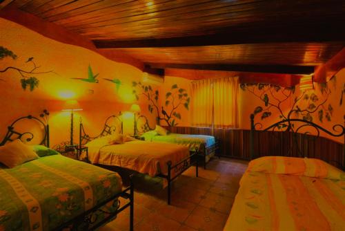 a bedroom with two beds and a painting on the wall at Hotel La Mansion Inn Arenal in Nuevo Arenal