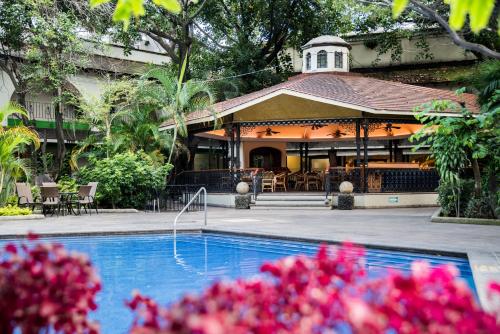 a house with a swimming pool in front of a house at Holiday Inn Guadalajara Expo Plaza del Sol, an IHG Hotel in Guadalajara