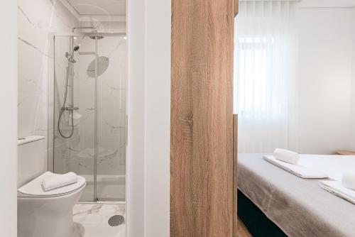 a white bathroom with a shower and a toilet at Hotel Grande Rio in Porto