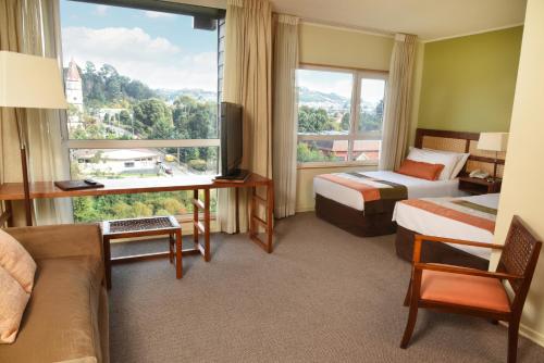 a hotel room with two beds and a large window at Solace Hotel Puerto Varas in Puerto Varas