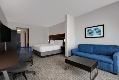 a hotel room with a blue couch and a bed at Holiday Inn Express & Suites - Milwaukee - Brookfield by IHG in Brookfield