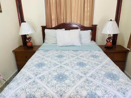 a bedroom with a blue and white bed with two lamps at Fosters West Bay Resort in West Bay