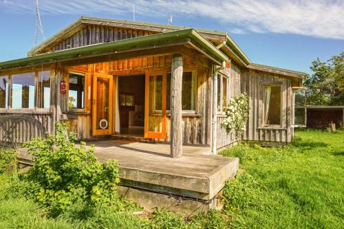 a small wooden house with a porch in a field at The Barn Cabins & Camp in Marahau