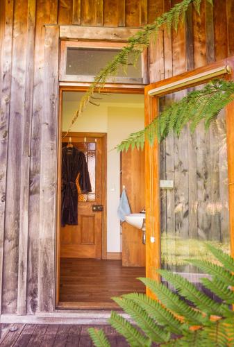 a wooden house with a door and a plant at The Barn Cabins & Camp in Marahau