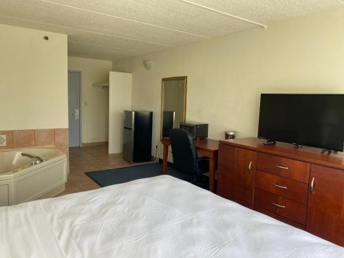 a hotel room with a bed and a desk with a television at Miami Gardens Inn & Suites in Miami