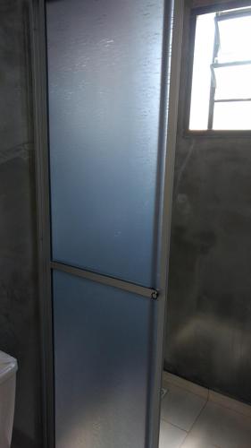 a door to a bathroom with a toilet and a window at Pousada Casa de Ferro in Passo de Torres