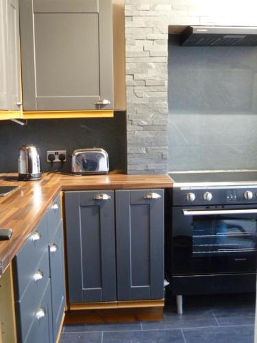 a kitchen with blue cabinets and a black oven at Charming Spacious Apartment, Kidderminster in Kidderminster