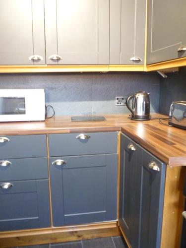 a kitchen with blue cabinets and a microwave at Charming Spacious Apartment, Kidderminster in Kidderminster