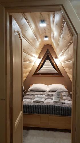 a bed in a tiny house with a wooden ceiling at Domek u Bizioma in Murzasichle
