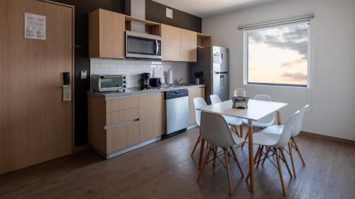 a kitchen with a table and chairs and a kitchen with a window at Staybridge Suites - Villahermosa Tabasco by IHG in Villahermosa