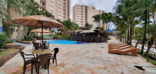 een patio met tafels en stoelen en een zwembad bij Apartamentos Ecologic PARK - Caldas Novas in Caldas Novas