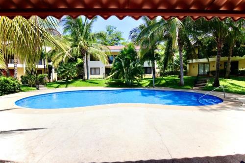 una gran piscina azul en un patio con palmeras en Las Colinas de Ocotal, en Coco