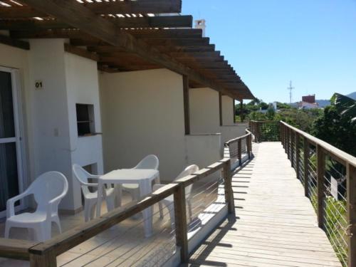 una terraza de madera con mesa y sillas. en Mirante dos Ingleses, en Florianópolis