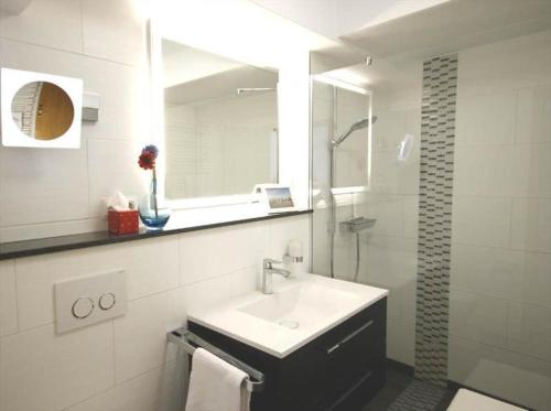 ein weißes Bad mit einem Waschbecken und einer Dusche in der Unterkunft Residenz Ostseewind - Wohnung 21 / 9659 in Kühlungsborn
