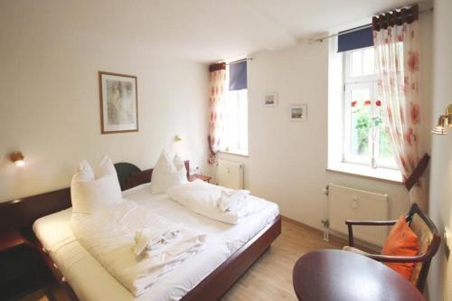 sypialnia z białym łóżkiem z krzesłem i oknem w obiekcie Residenz-Ostseewind-Wohnung-21-9659 w mieście Kühlungsborn