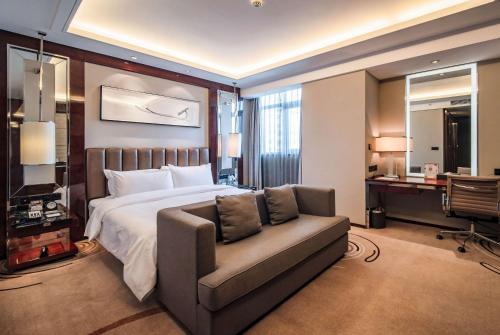 a bedroom with a bed and a couch and a desk at Ramada Changzhou North Hotel in Changzhou