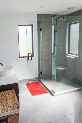 a bathroom with a glass shower with a red rug at The Barn Cabins & Camp in Marahau